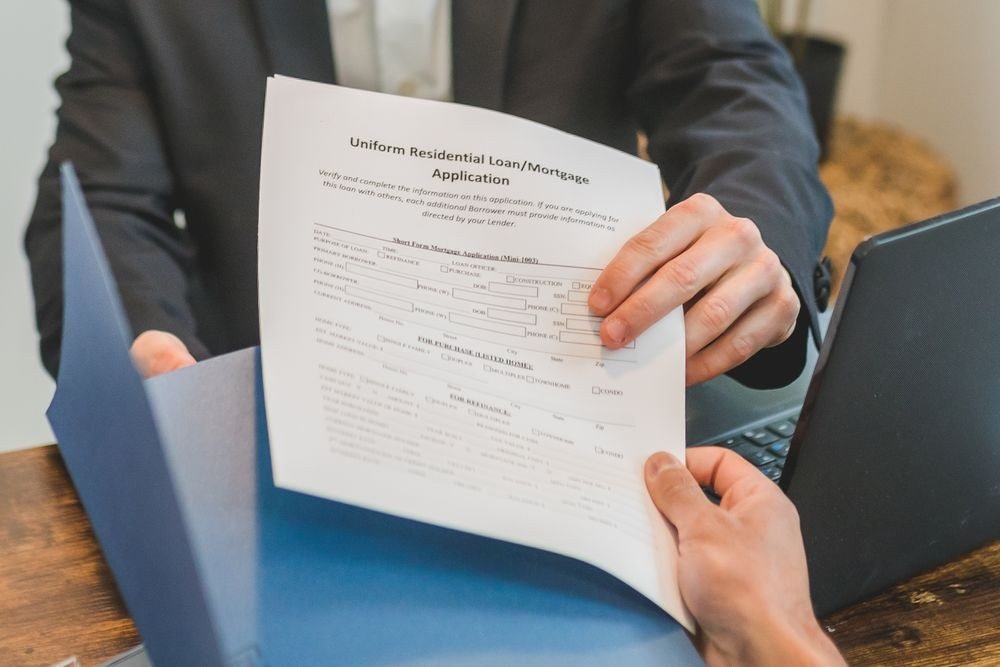 A residential loan and mortgage application being handed across a desk, part of the light DSCR document checklist