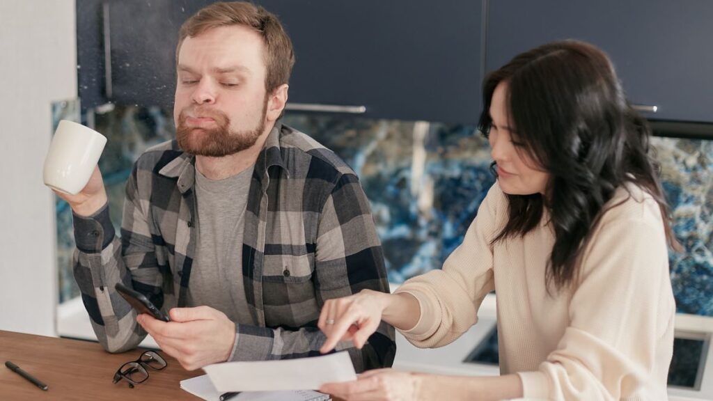 A couple at their kitchen table reviewing a home insurance renewal bill with concern