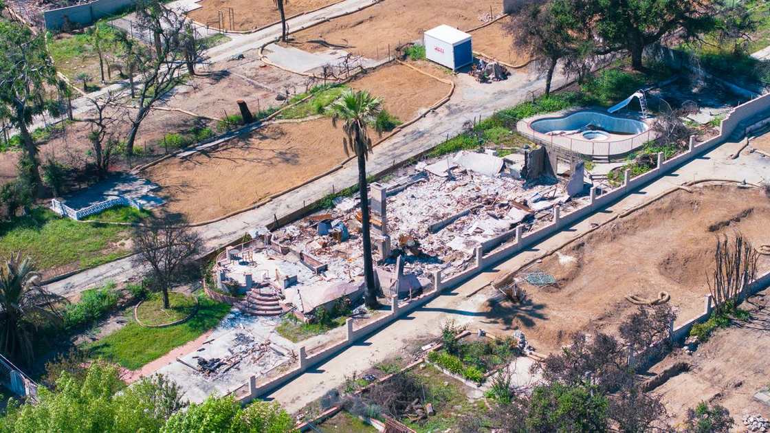Aerial view of a home reduced to rubble by wildfire in a burned-out neighborhood